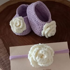 Handmade lavender crochet baby booties with soft white crochet flower details, paired with a matching lavender baby headband featuring a white crochet flower, displayed on a wooden tray with Calissi Made With Love branding.
