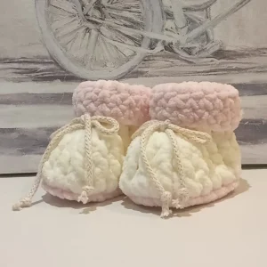 Handmade crochet baby product, premium crochet baby booties in soft cream and blush tones, perfect for newborns and infants.