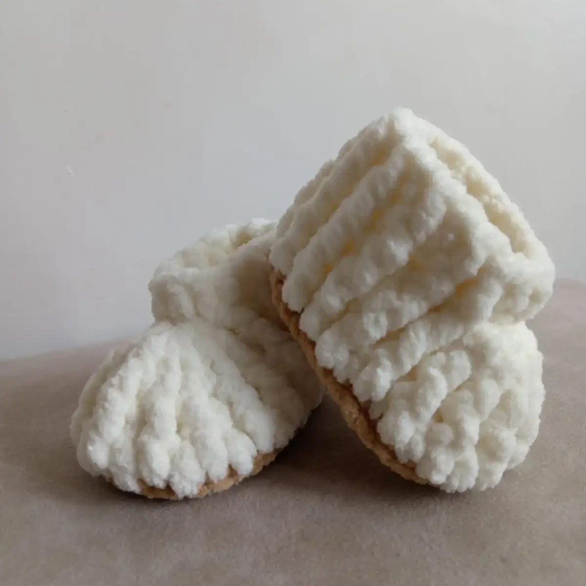 Handmade crochet baby booties in soft cream color with ribbed texture, cozy plush yarn, lightweight and comfortable newborn footwear by Calissi.